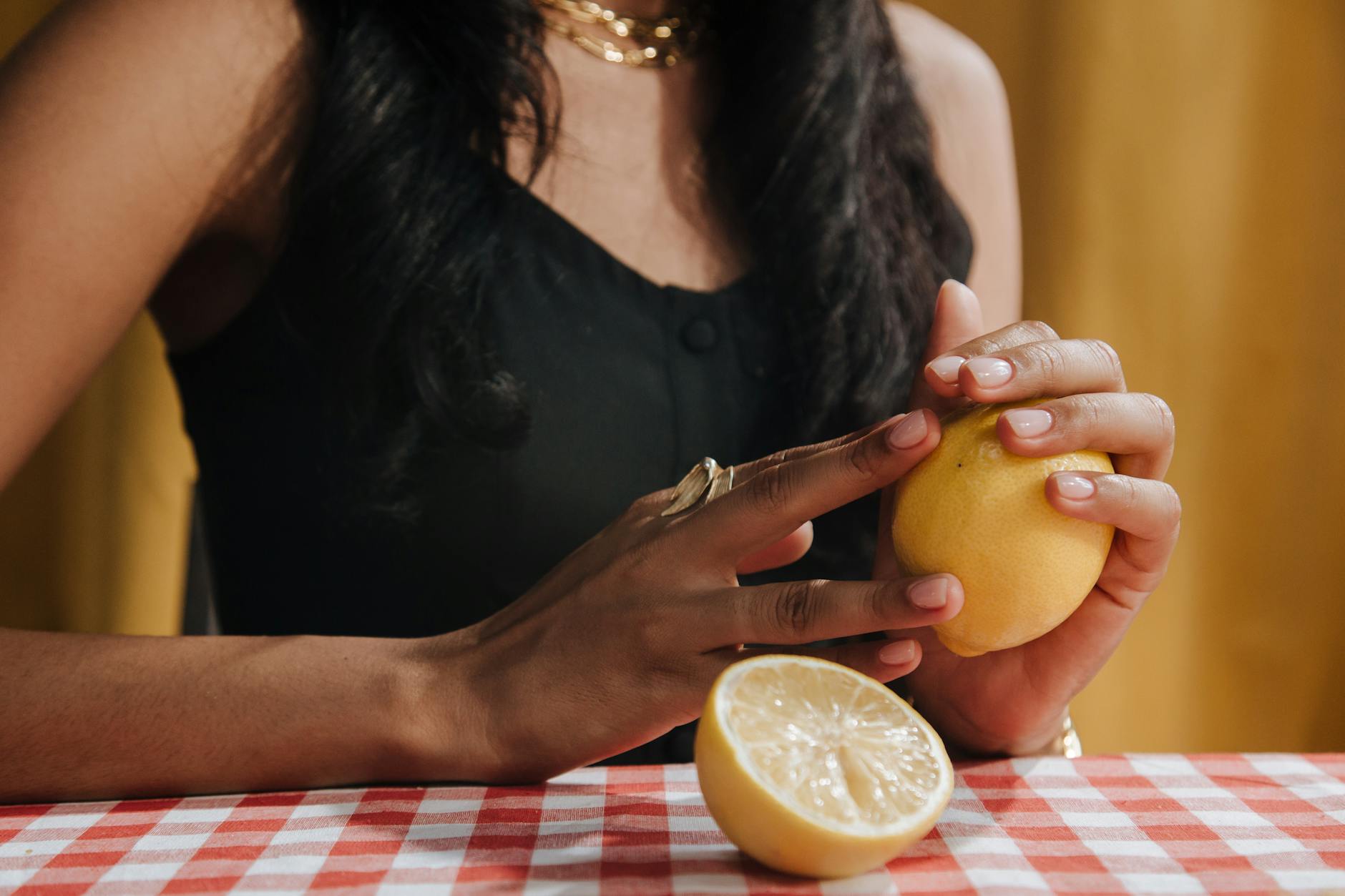 Hand holding a fresh lemon against a bright yellow background, symbolizing renewal and recovery