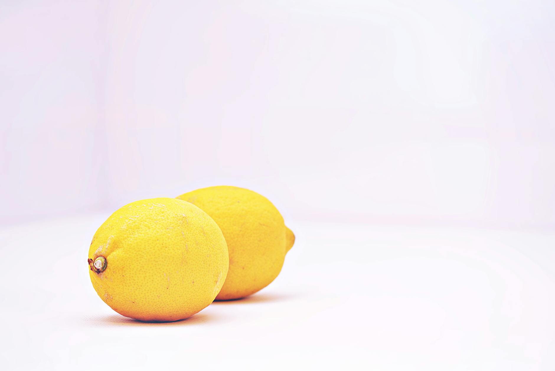 Two vibrant lemons placed against a minimalistic white background, symbolizing freshness and healing