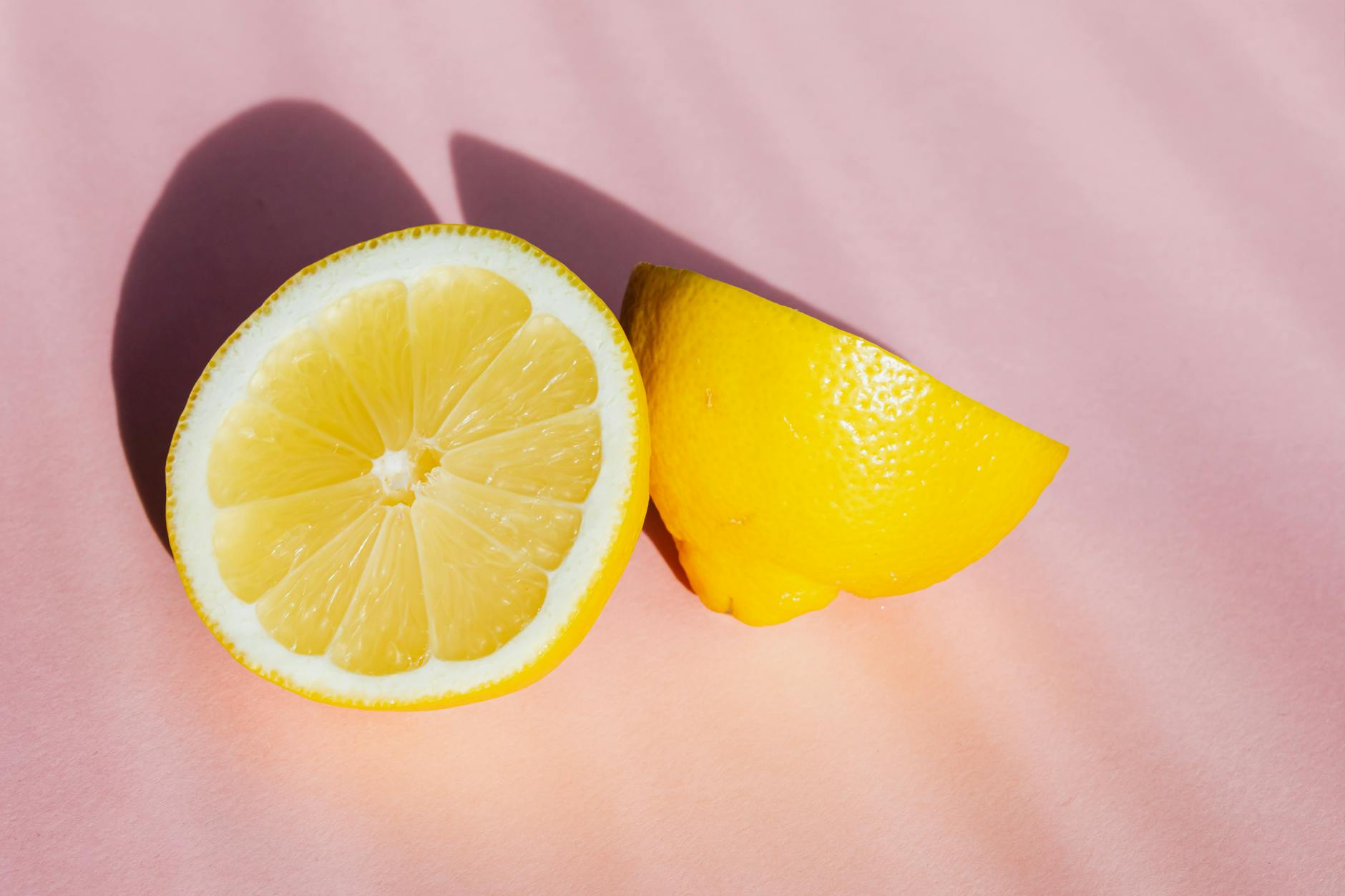 Hand holding a fresh lemon against a bright yellow background, symbolizing fresh approaches to pleasure