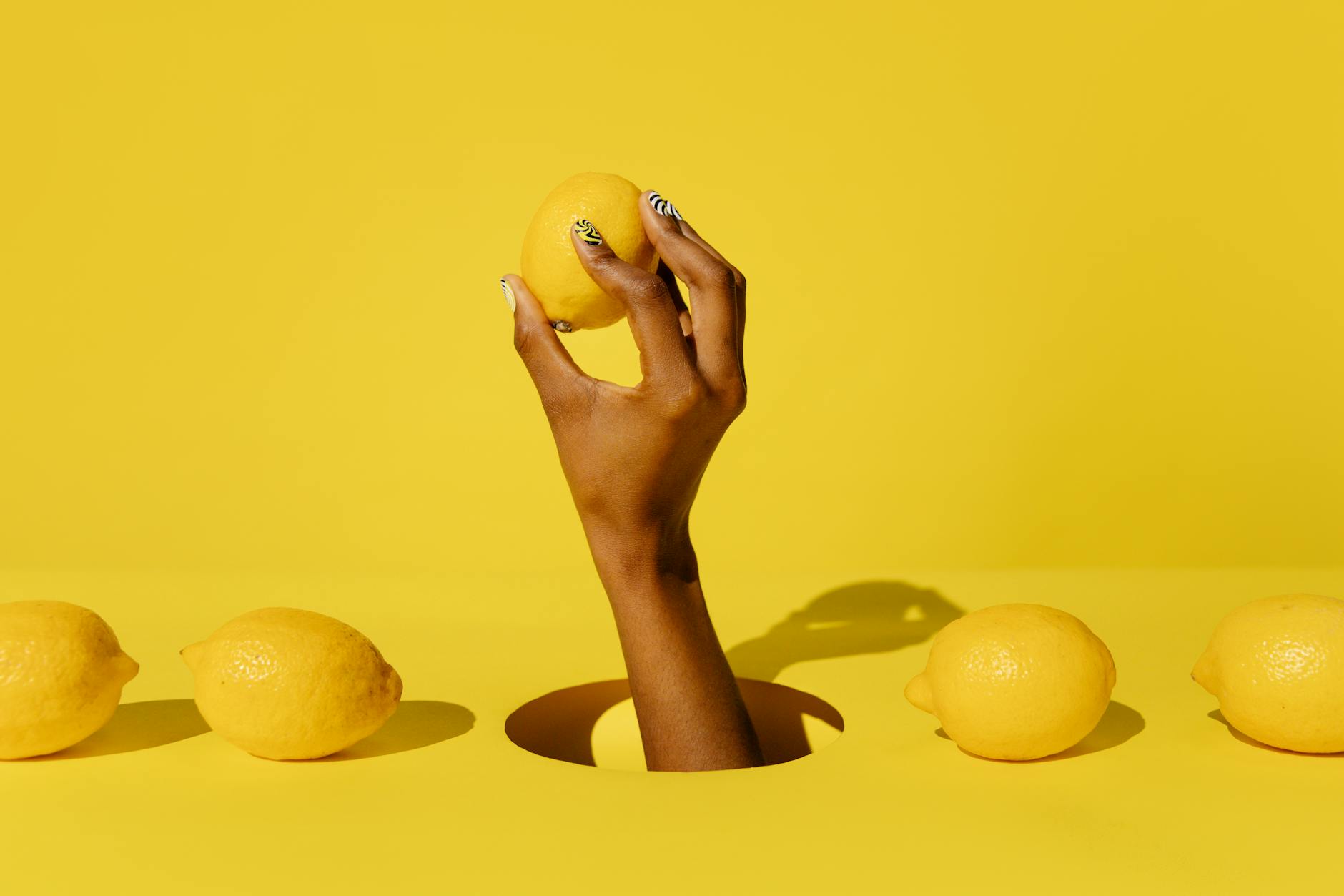 A hand holding a bright lemon against a vivid yellow background, symbolizing fresh starts and renewal