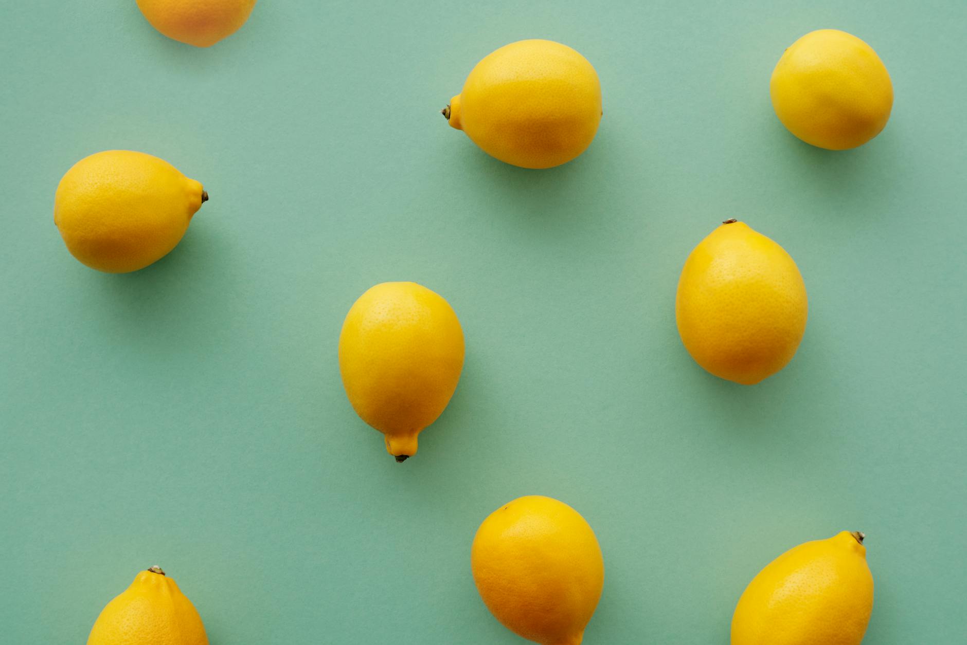 Fresh lemons arranged on a pastel green background in a flat lay composition