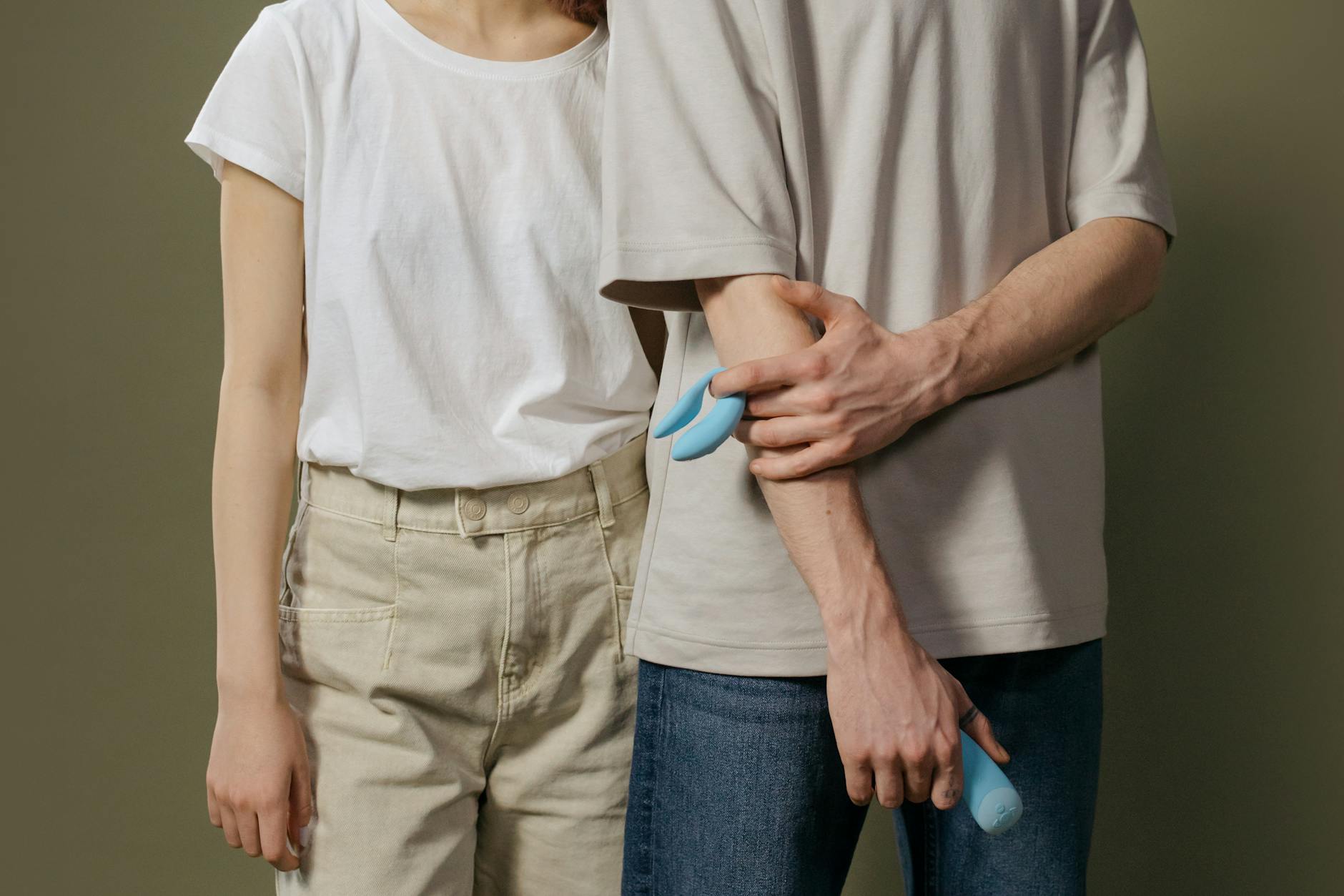 A couple holding a blue vibrator together, symbolizing modern intimacy and pleasure.