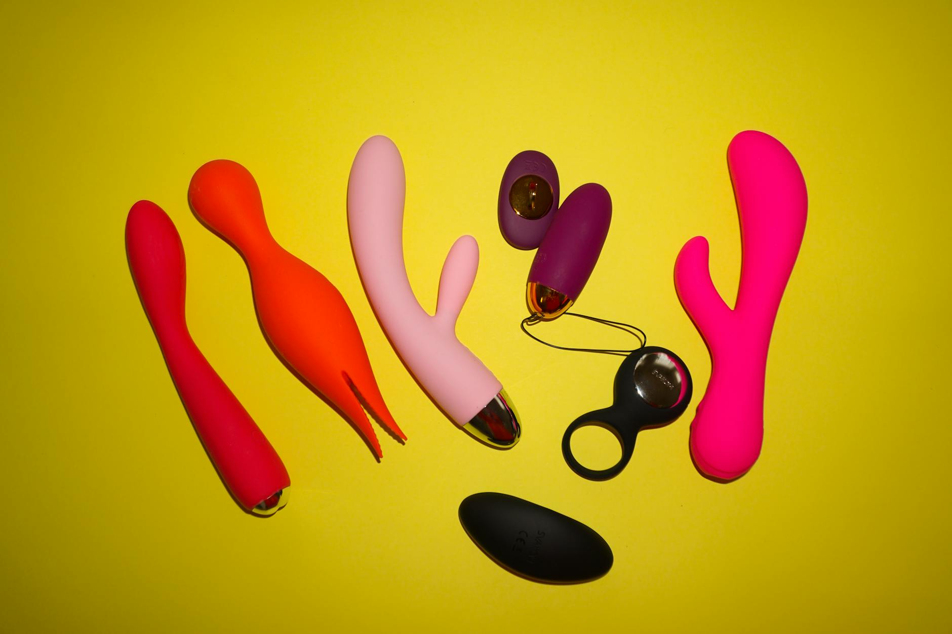 Close-up view of various colorful silicone vibrators arranged on a dark surface